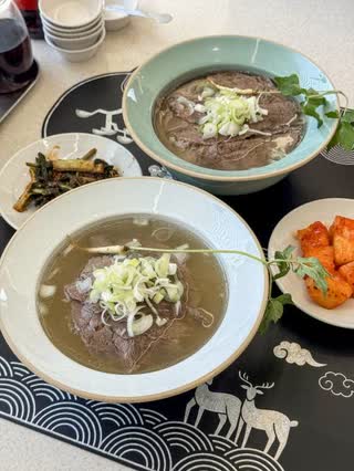 The celadon gomtang bowl served under its lid, with banchan alongside