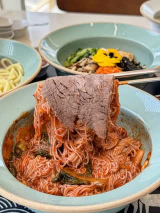 Gomtang, cold noodles and bibimbap set out together on one table